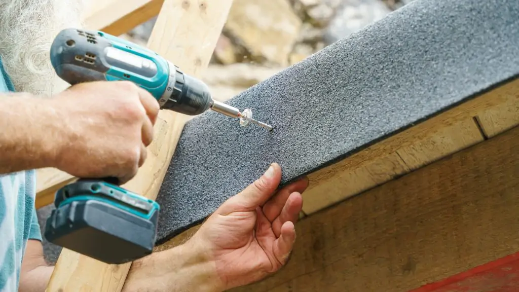 Traditional Roofing Materials, a man repairs the roof, tightens the self-tapping screw with a screwdriver, property managers, tiled roofs, roof inspection, maintenance in gold coast, free quote, property leaks, inspect, protect