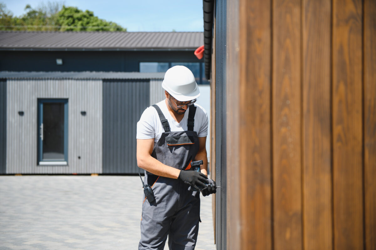 Construction Worker Assembling Modular House Exterior in Daytime