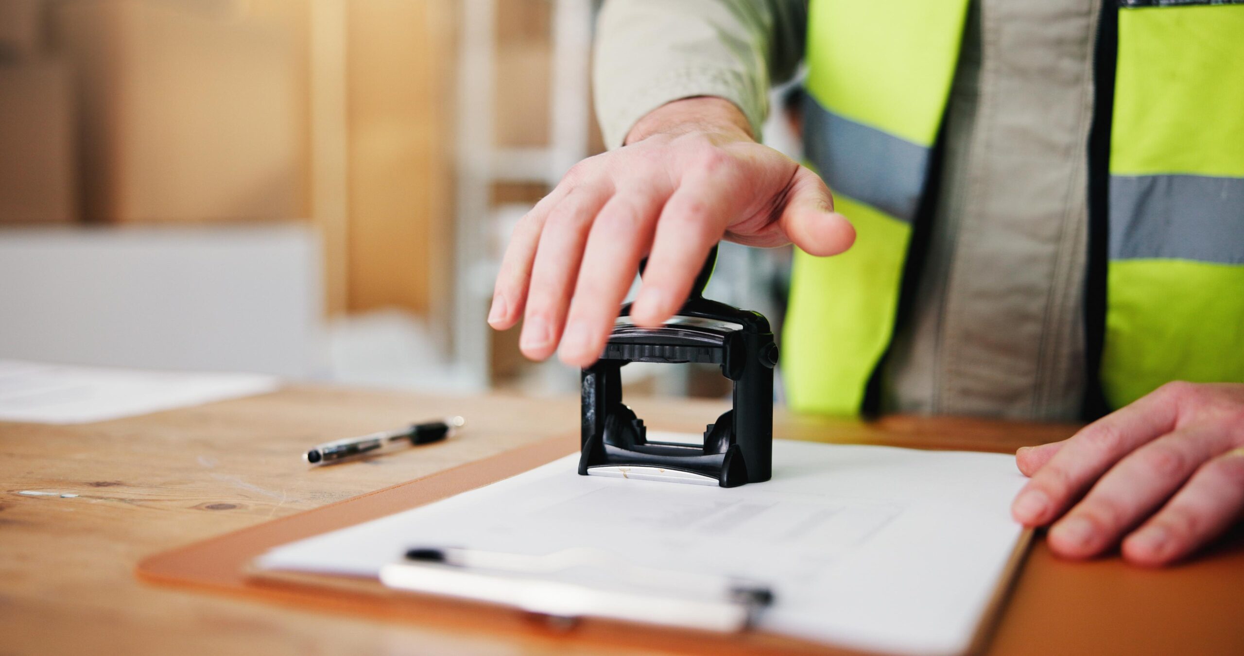 Worker in High-Visibility Vest Stamping a Document in a Logistics Warehouse