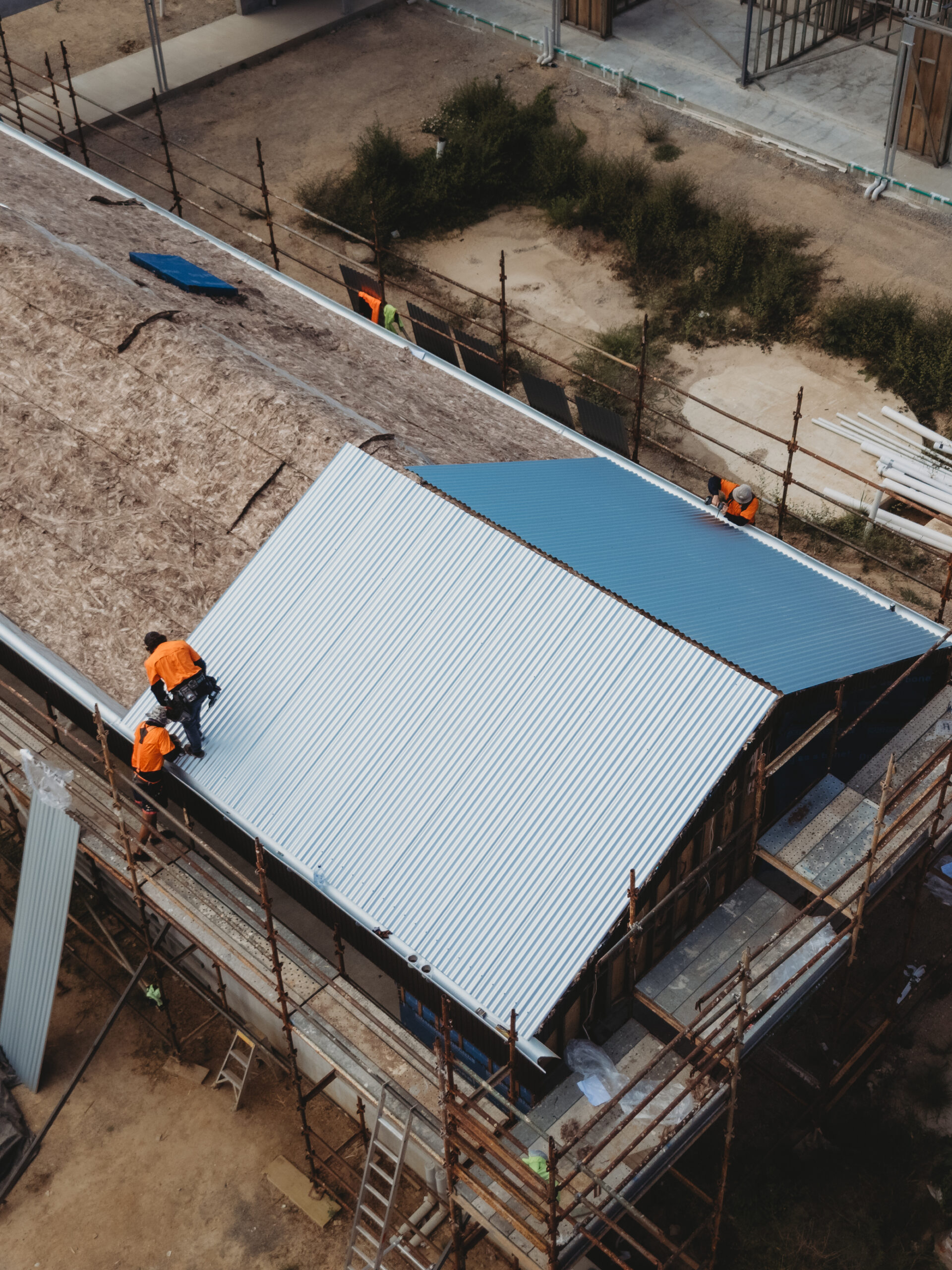 Roofers installing new metal roofing sheets on a residential construction project