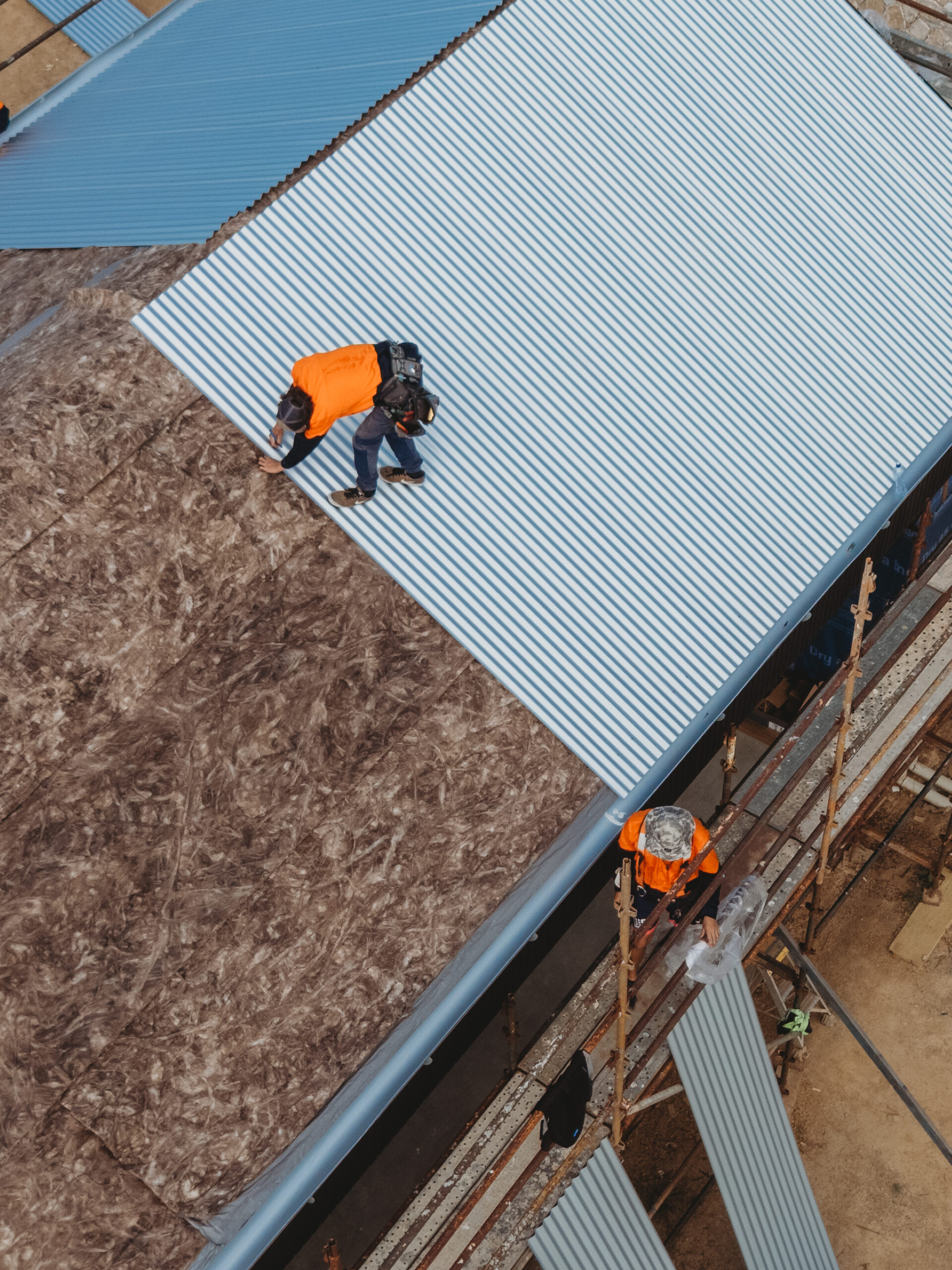 Roofer fitting corrugated metal roof sheets during a residential roof installation