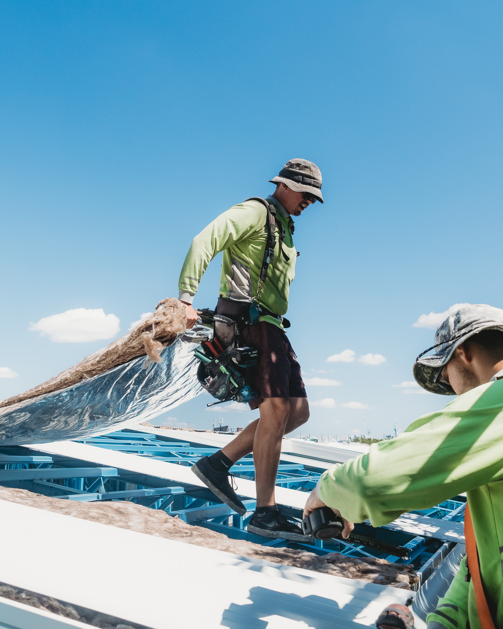 Roofer installing insulation beneath metal roofing on a new roof