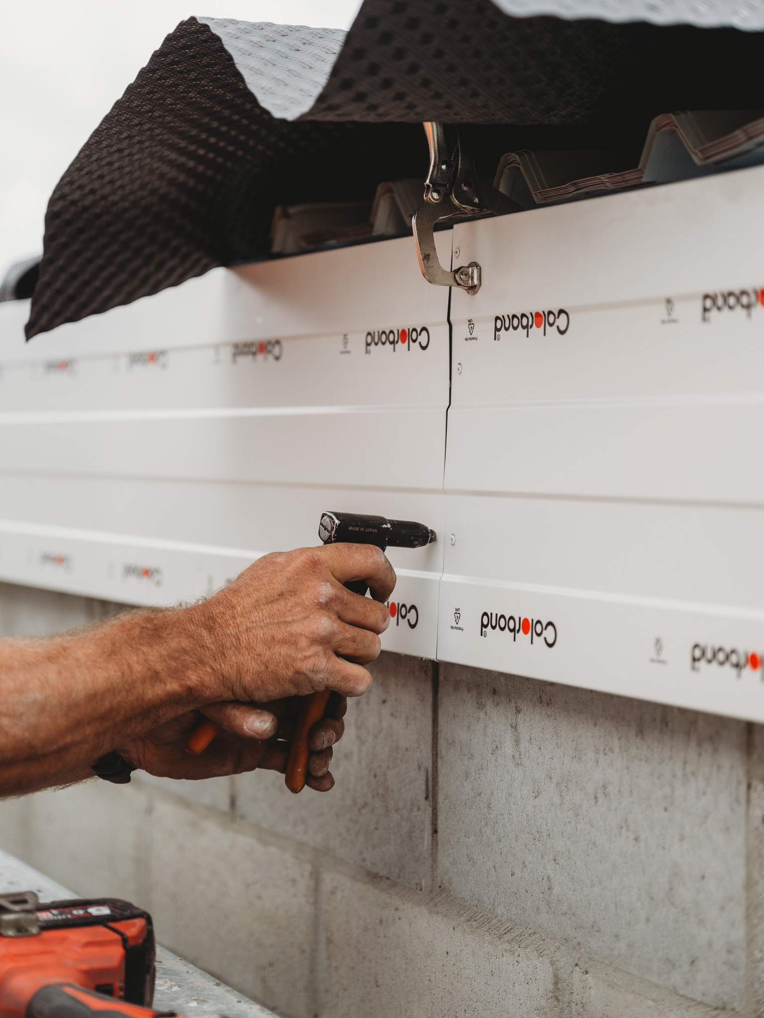Close-up of tradesperson installing Colorbond fascia on a roofing project