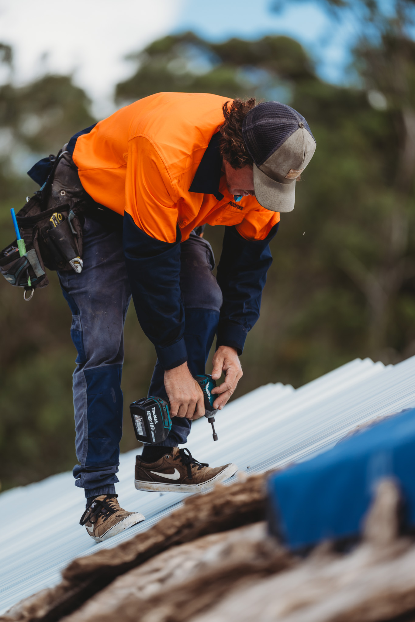 Roofer fastening corrugated metal roof sheets during installation