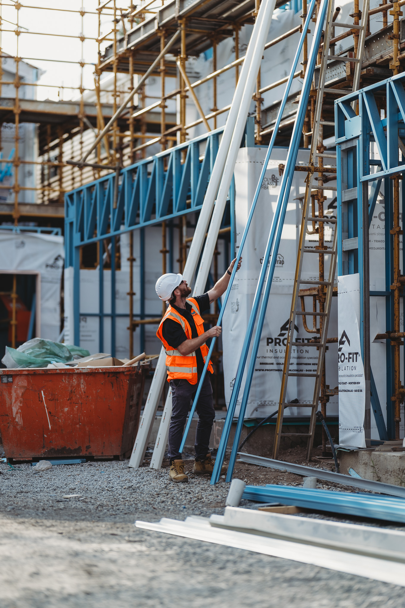 Construction worker handling metal framing materials on a building site