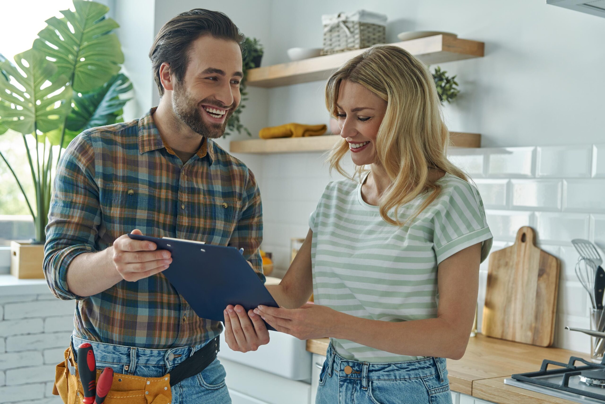Man and Woman Discussing a Clipboard in a Kitchen