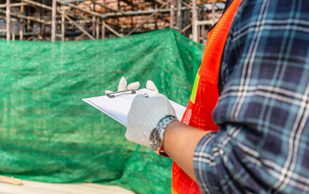 Construction Worker Writing on Clipboard at Construction Site
