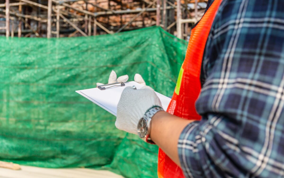 Construction Worker Writing on Clipboard at Construction Site
